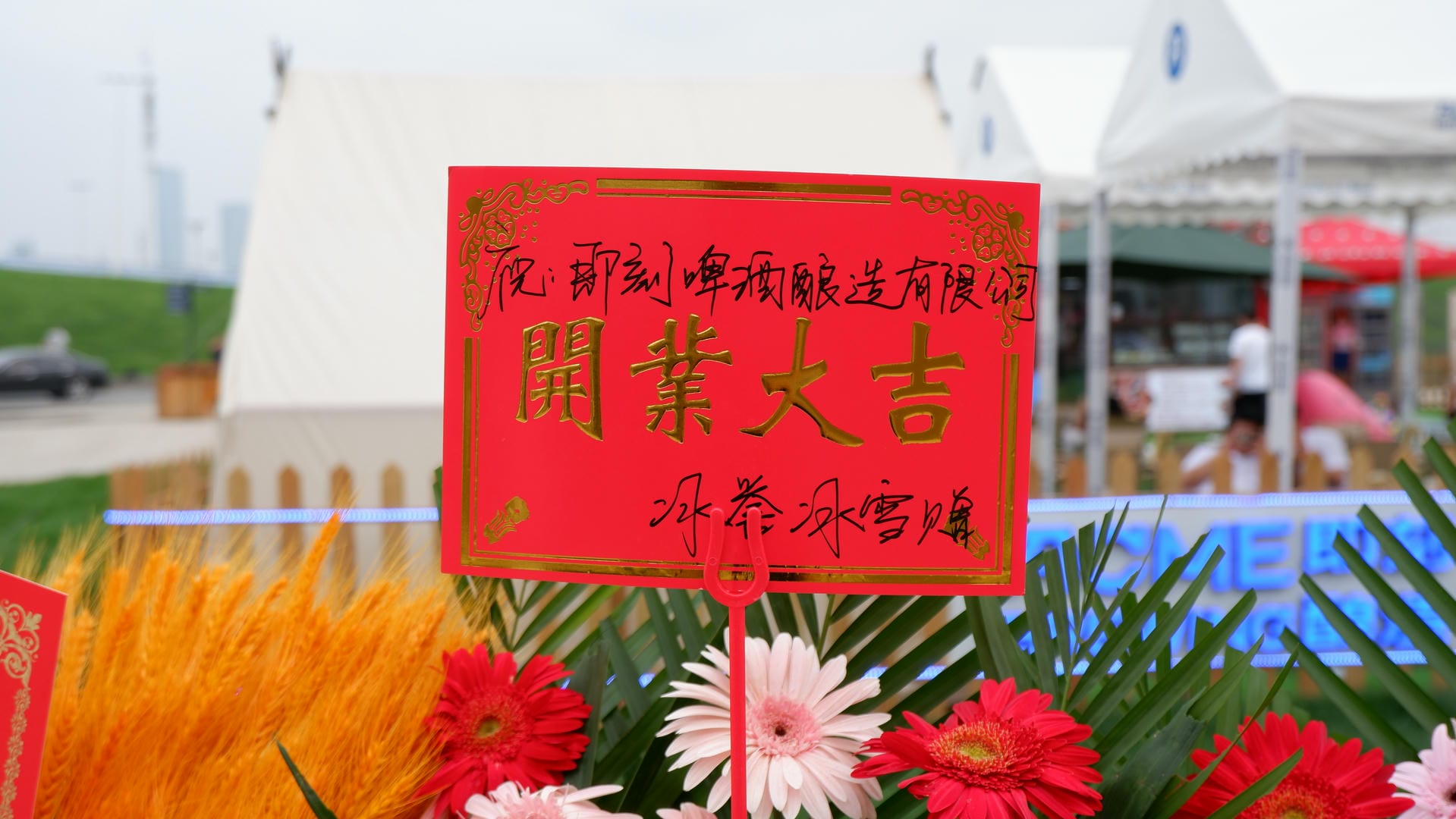 there is a red sign with chinese writing on it in front of a bunch of flowers