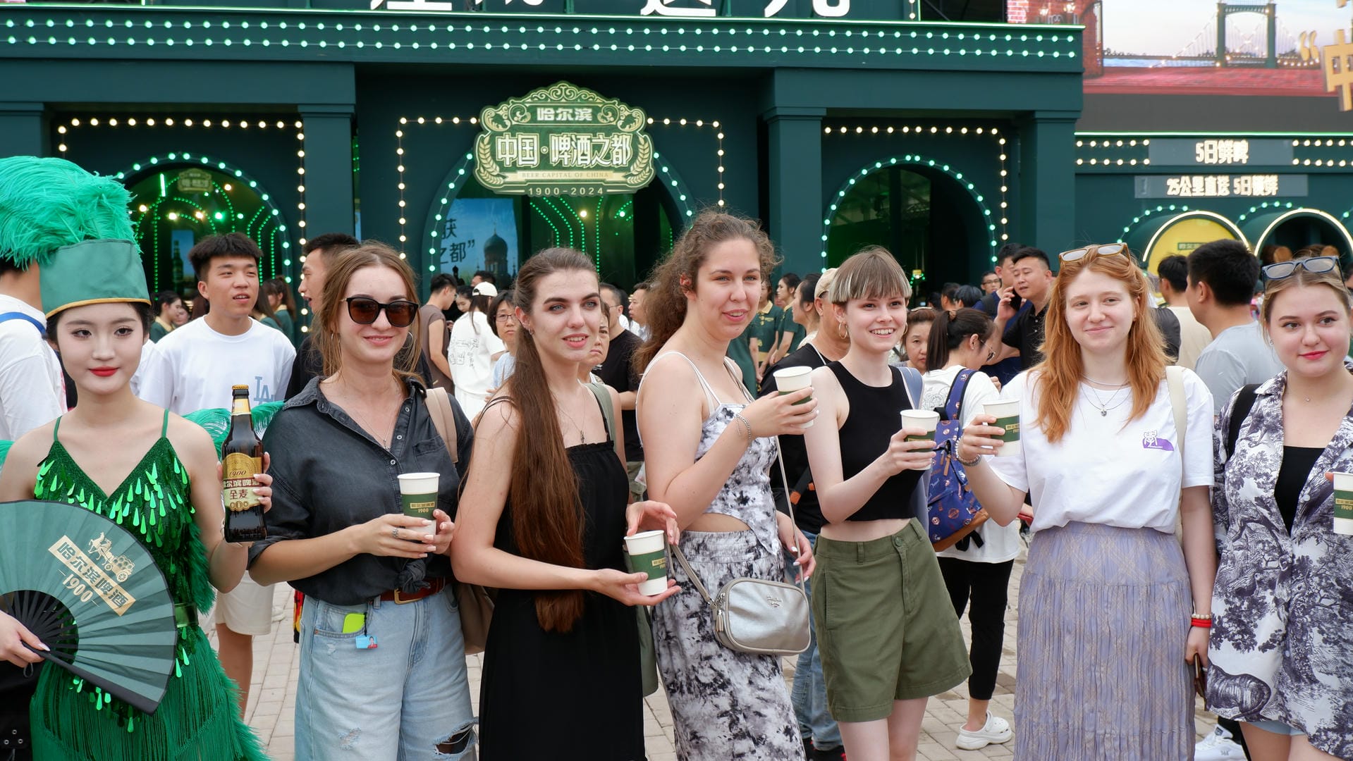 several women are standing outside of a building with a green hat