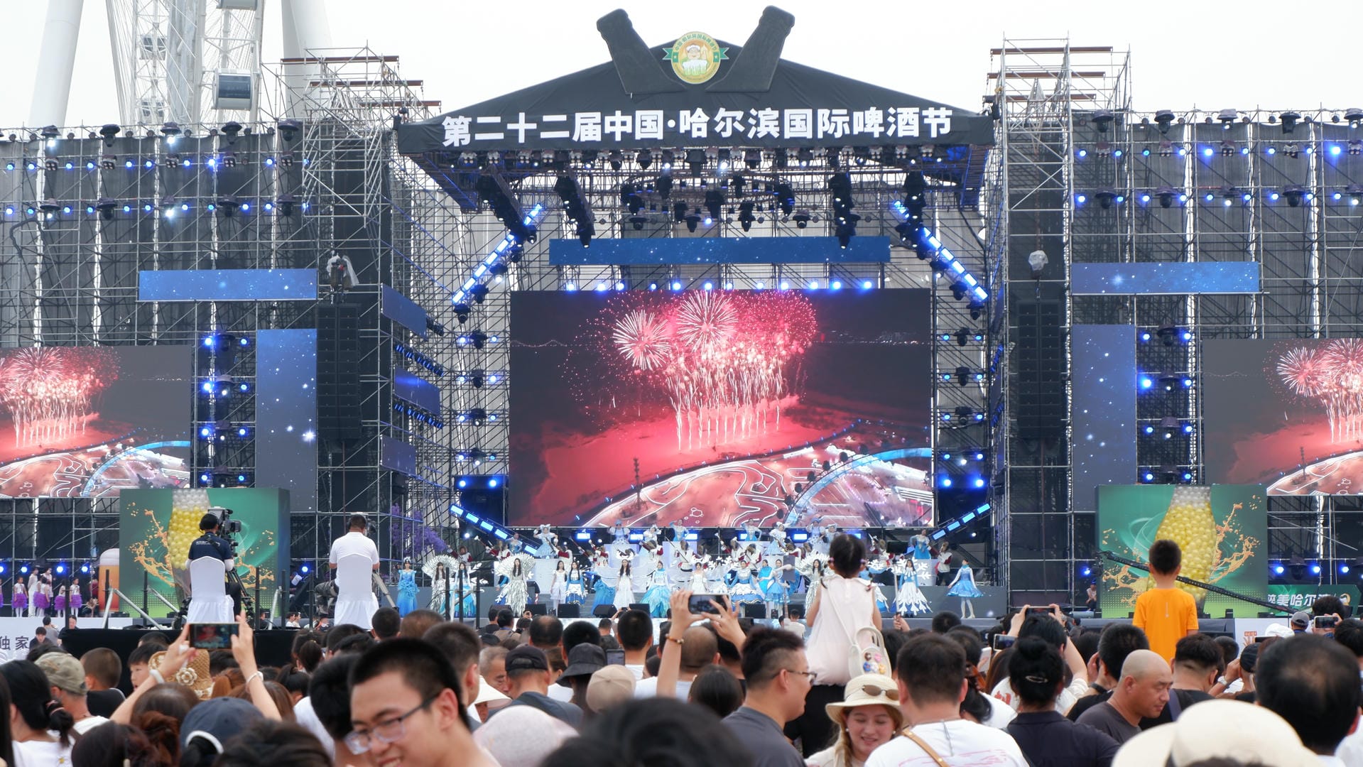 people are gathered around a stage with fireworks and a large screen