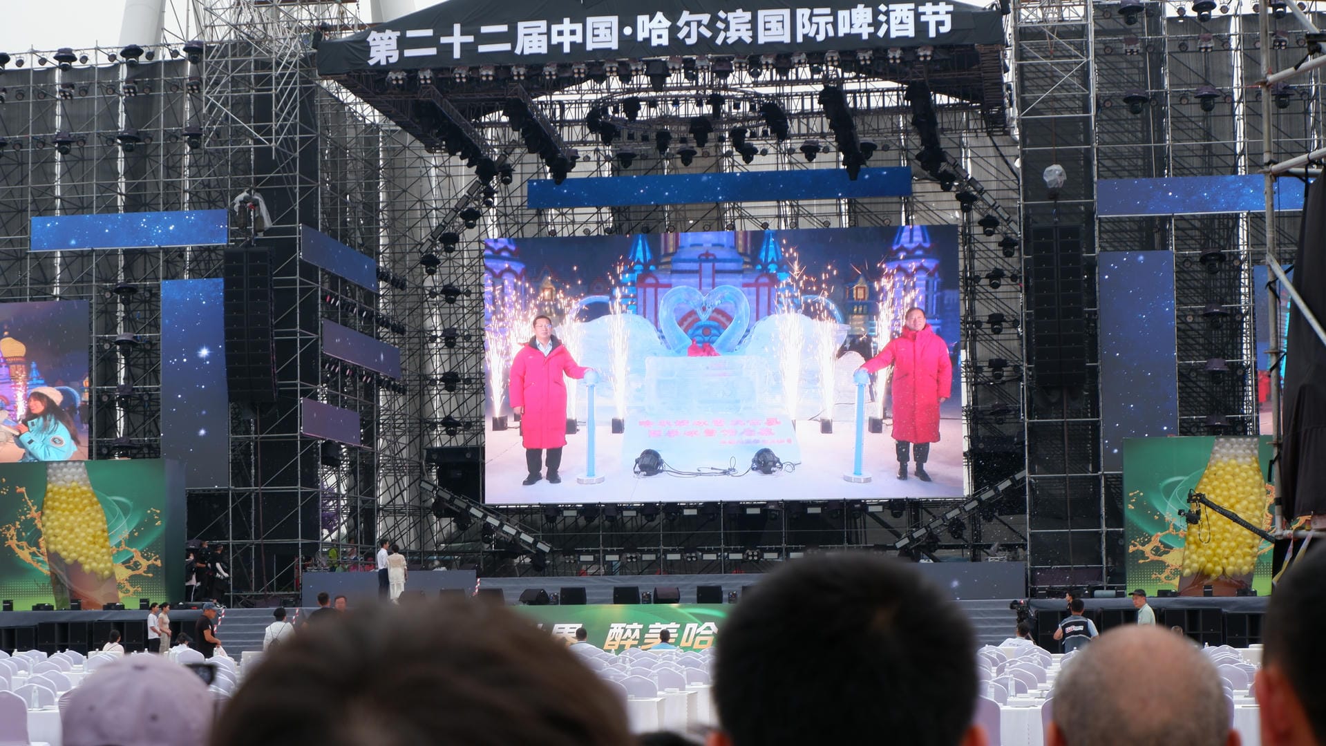 people are watching a performance on a large screen in a stadium