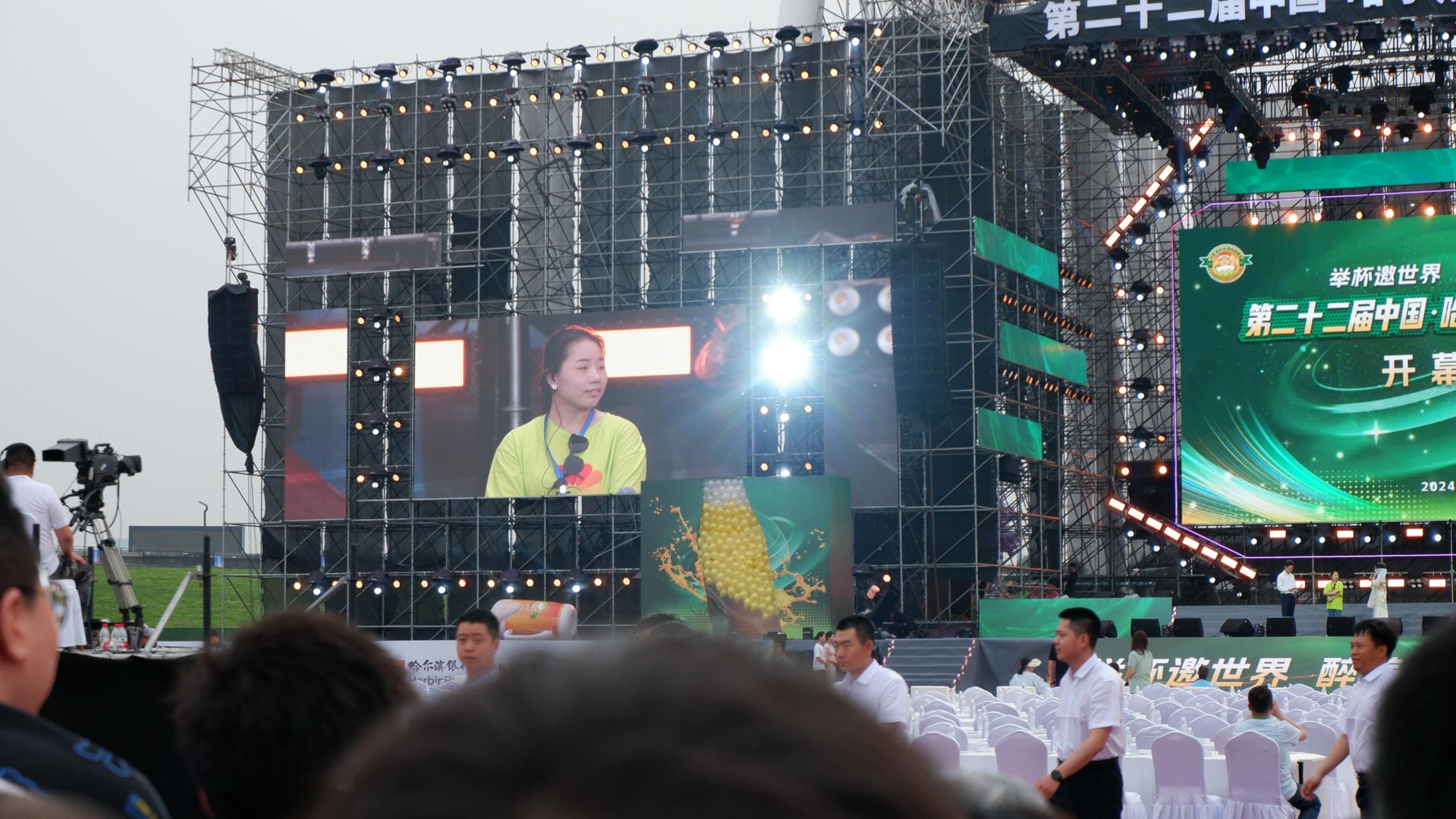 there is a large screen with a woman on it in a crowd