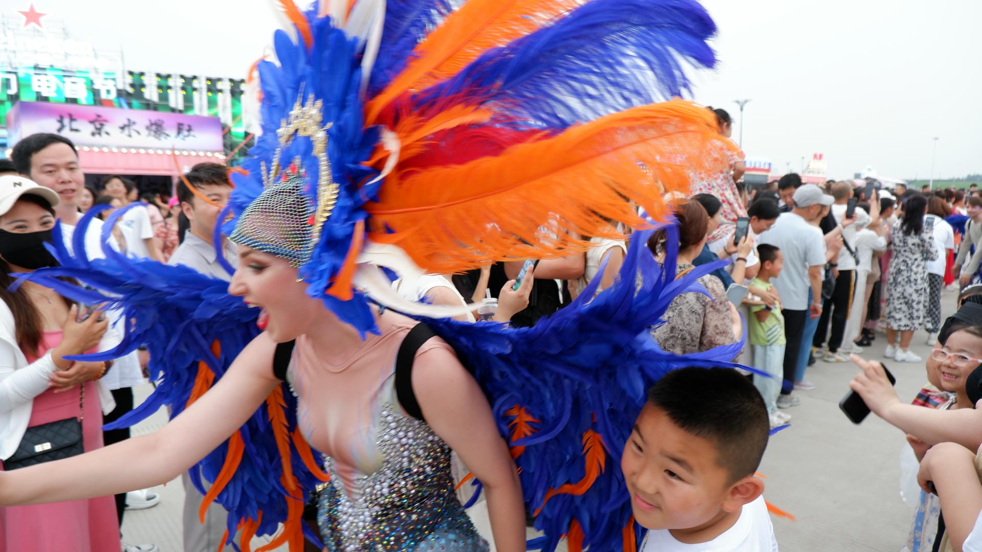 woman in a colorful costume with a child in front of a crowd