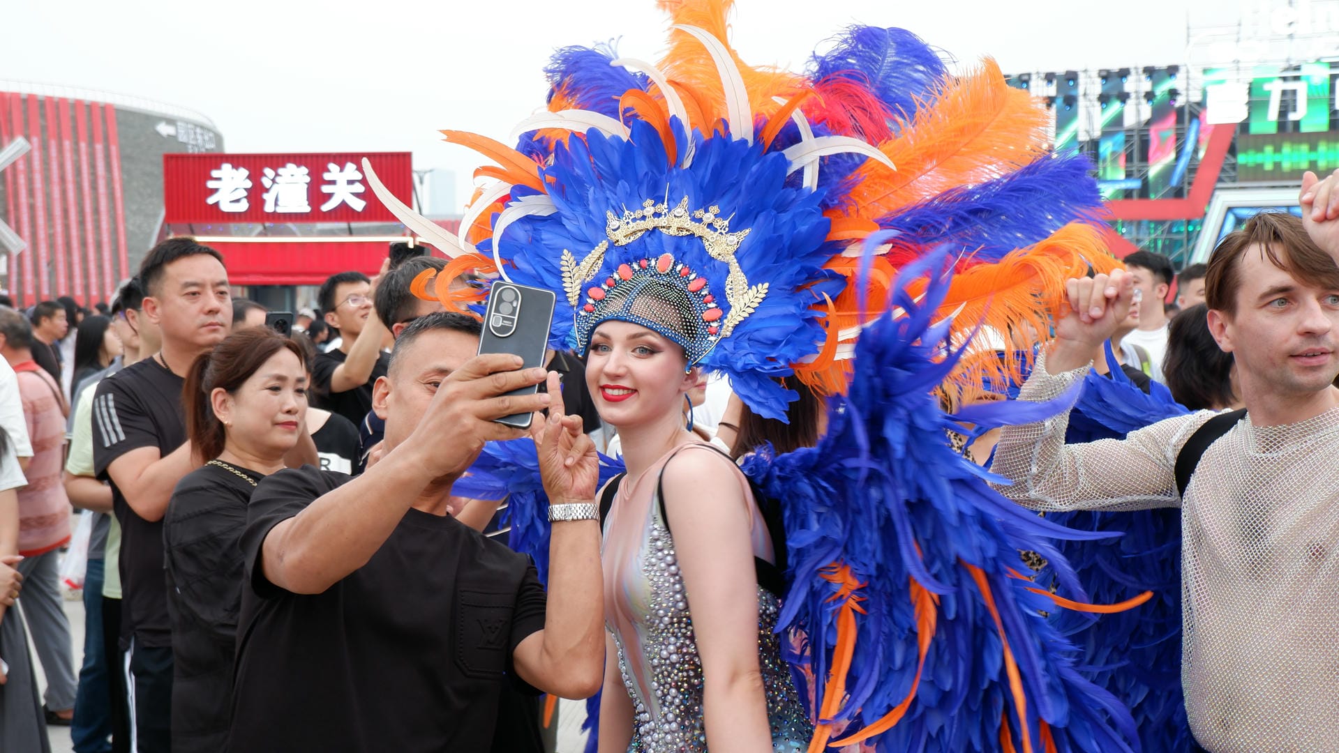 woman dressed in a blue and orange costume taking a picture with a cell phone