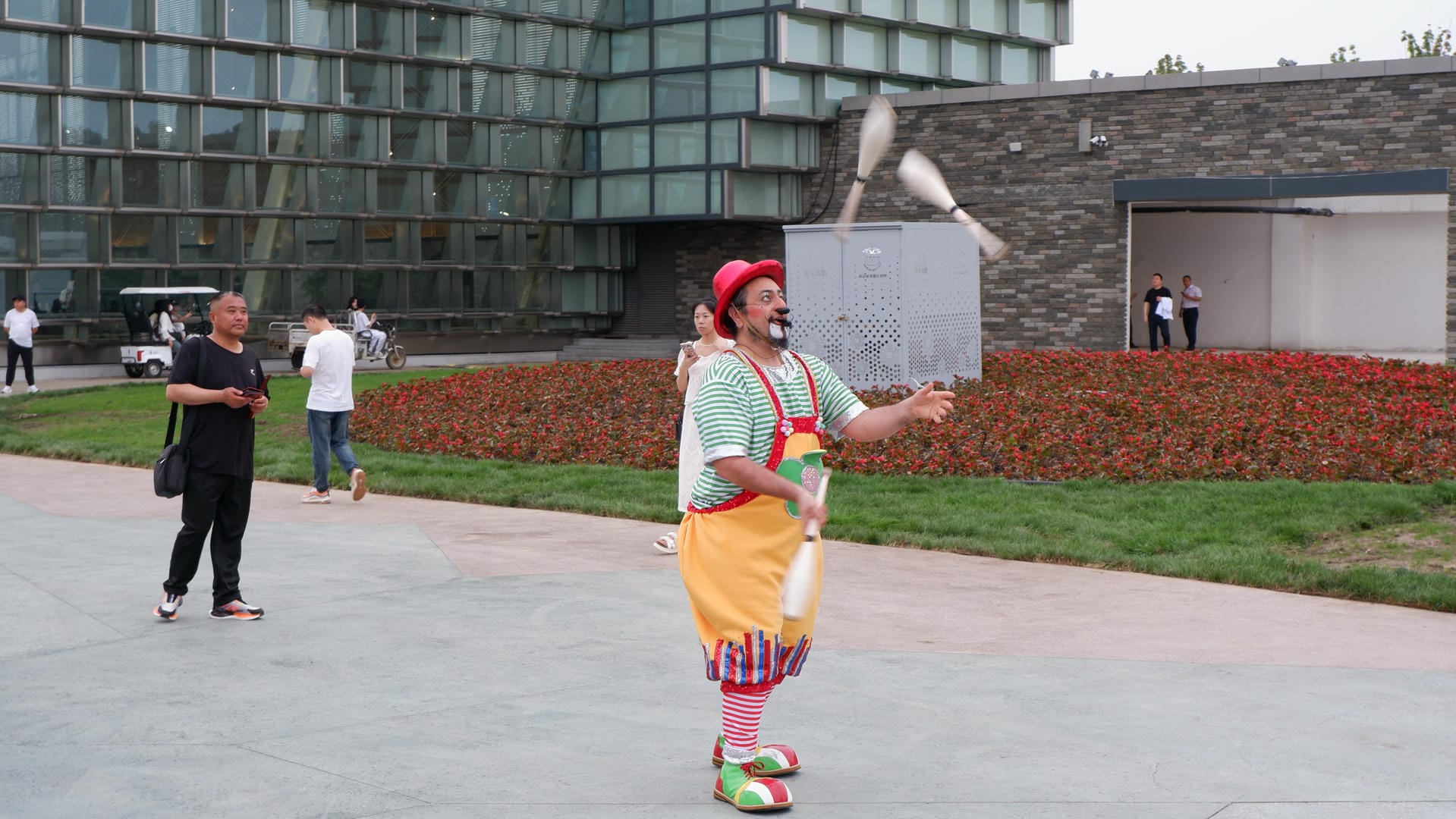 clown juggling with a white juggling stick in front of a building