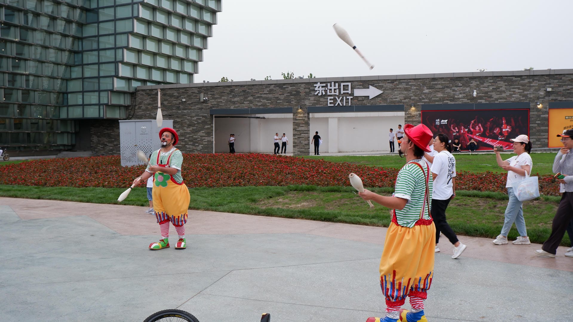 people are walking around in a park with a kite flying in the sky