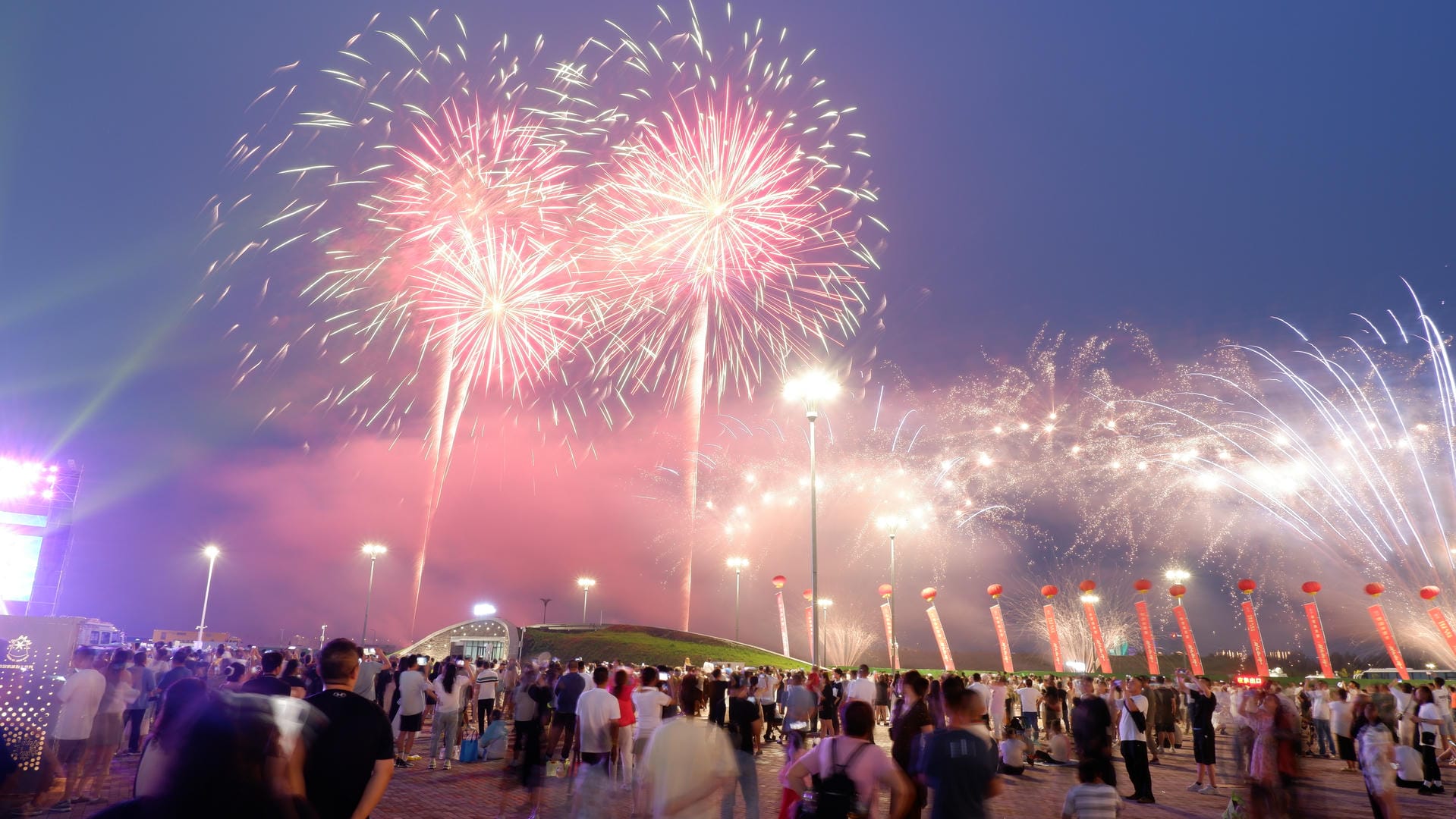 fireworks are lit up in the sky above a crowd of people
