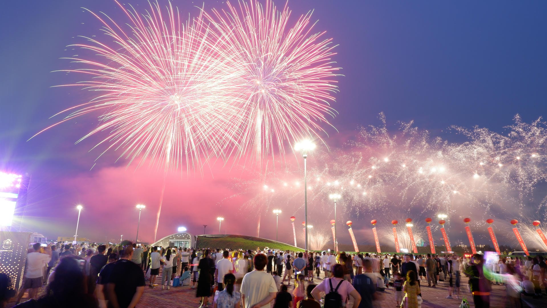 fireworks are lit up in the sky above a crowd of people