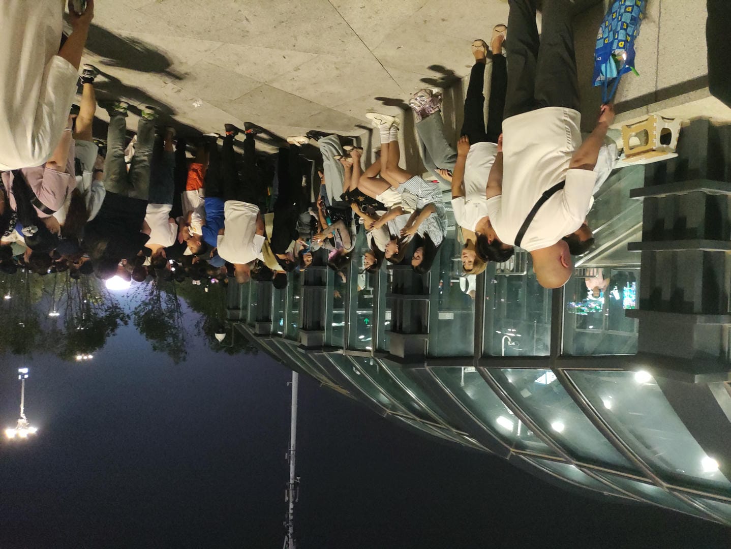 people standing in line at a bus stop waiting for their bus