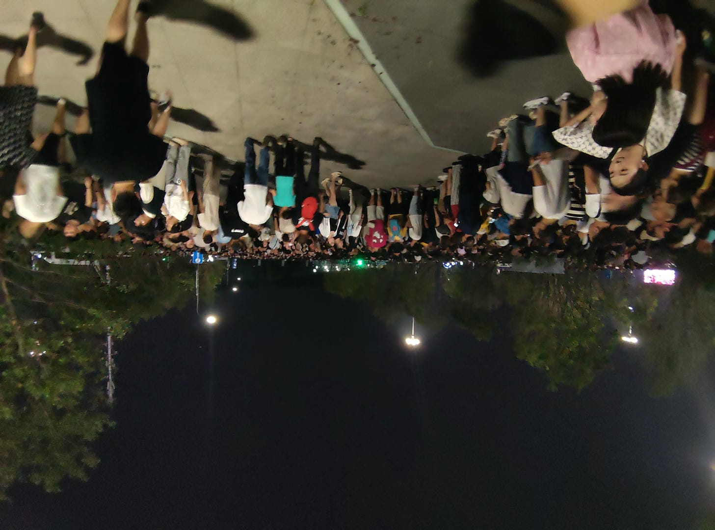 people are standing in a parking lot at night with a lot of lights