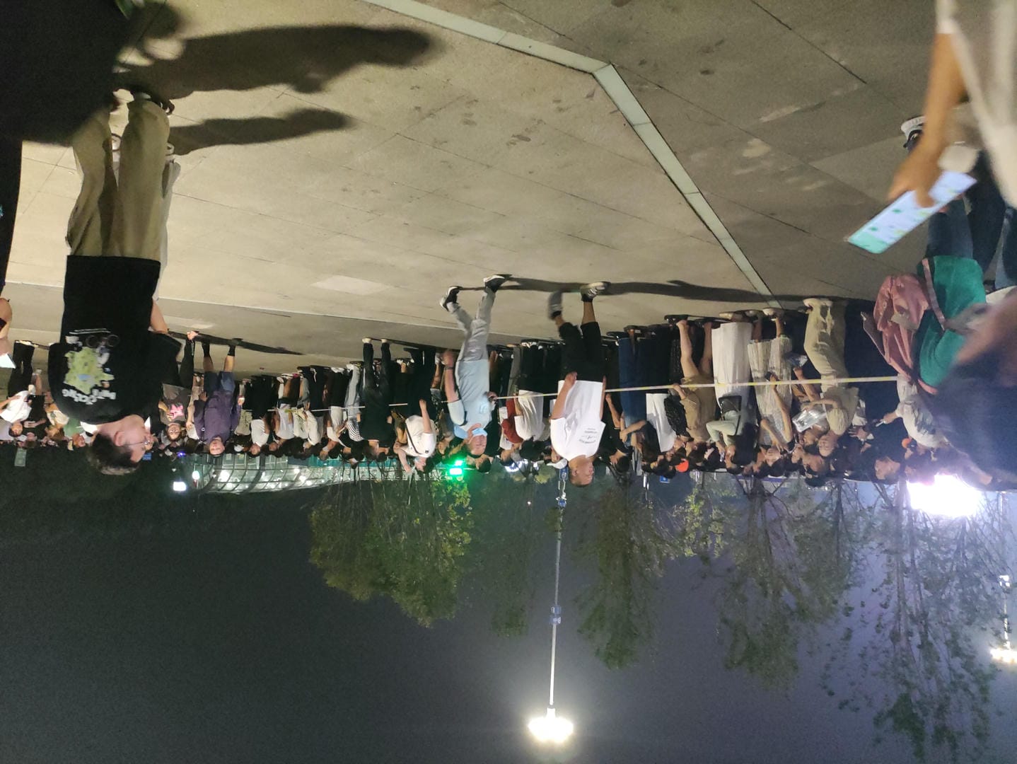 people standing in a parking lot at night with a crowd of people