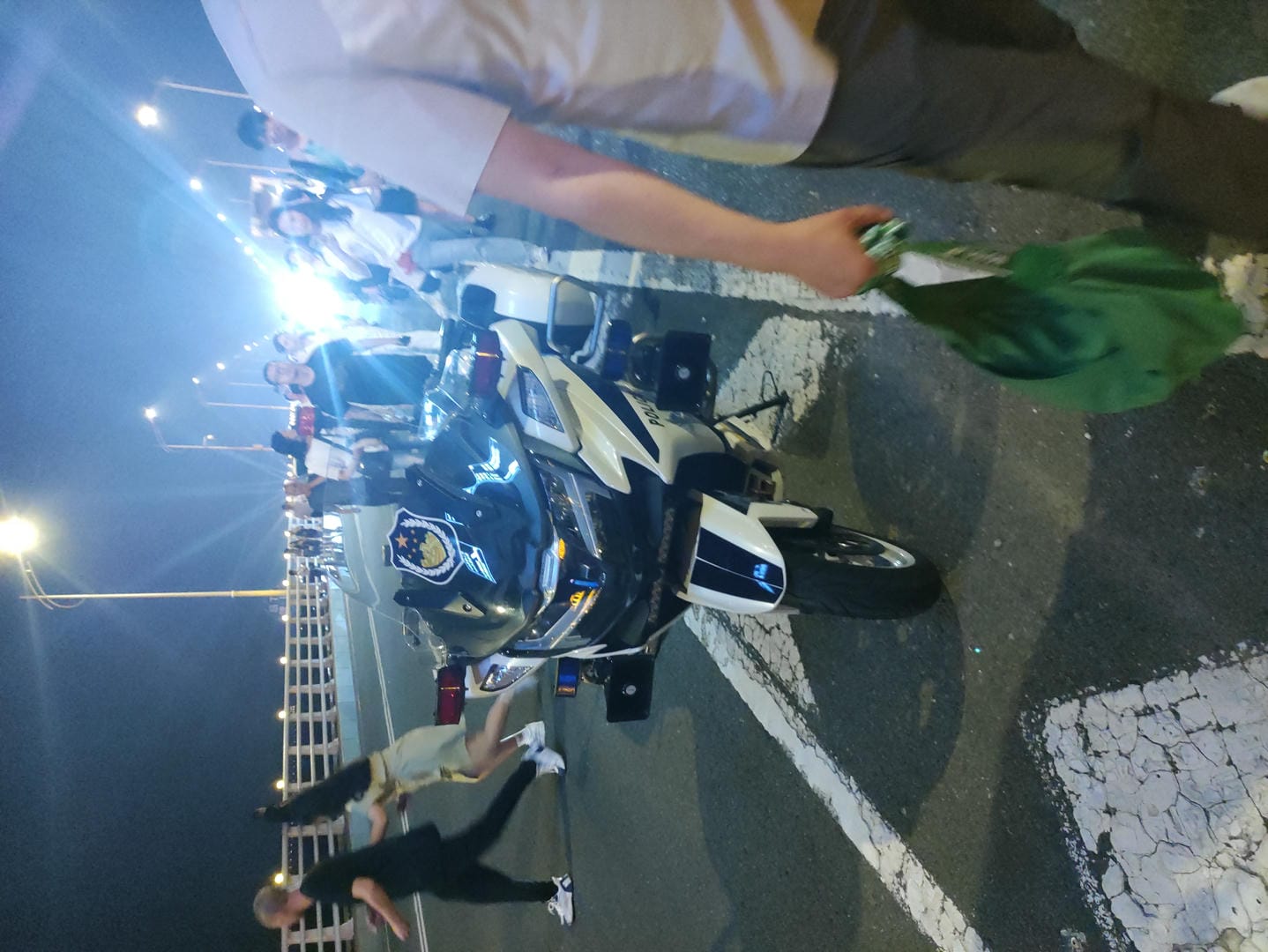 there is a man walking by a motorcycle with a bag