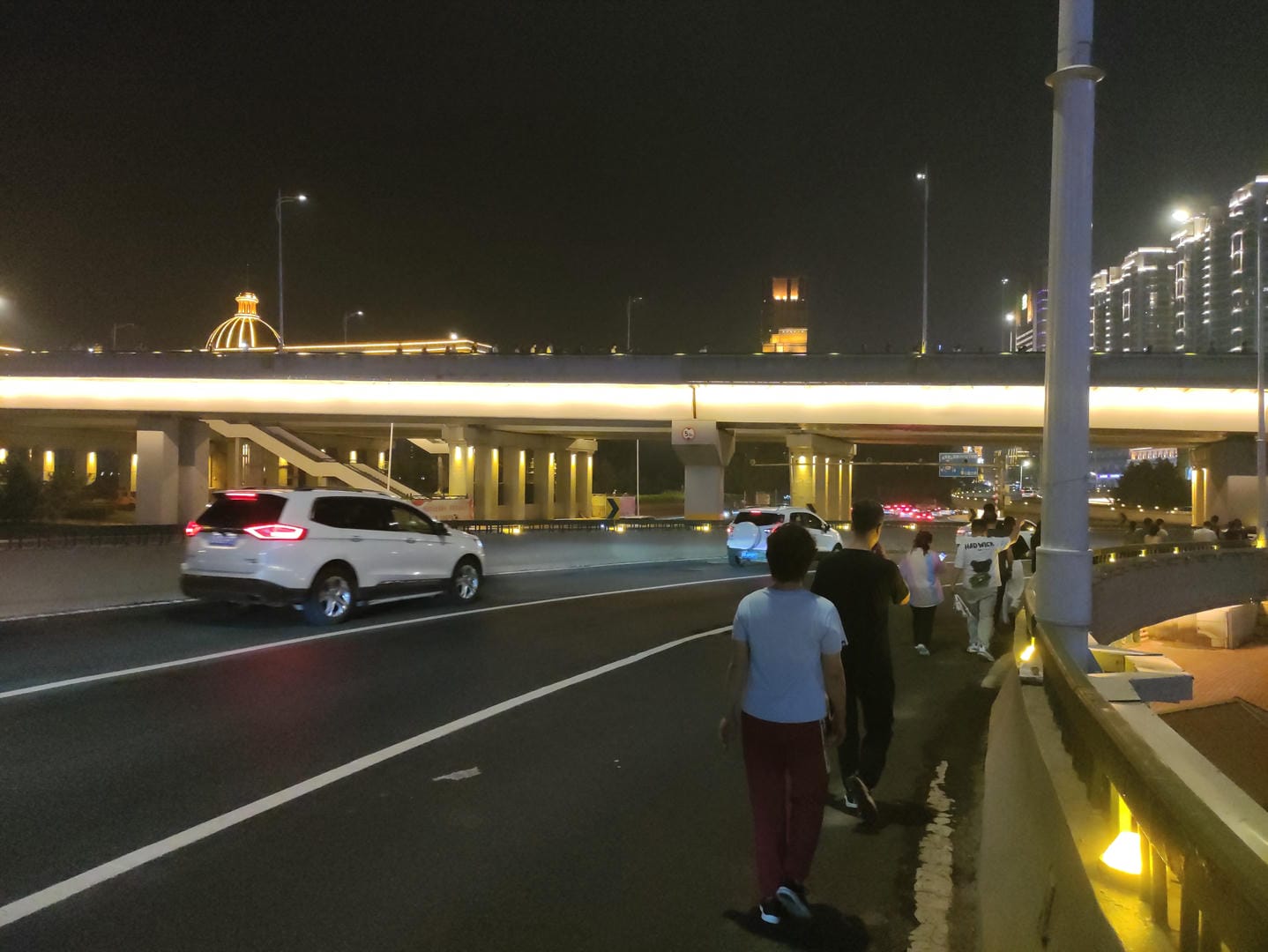 people standing on the side of a road next to a highway